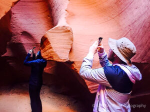 Woman and teenage boy taking cell phone pictures in Lower Antelope Canyon