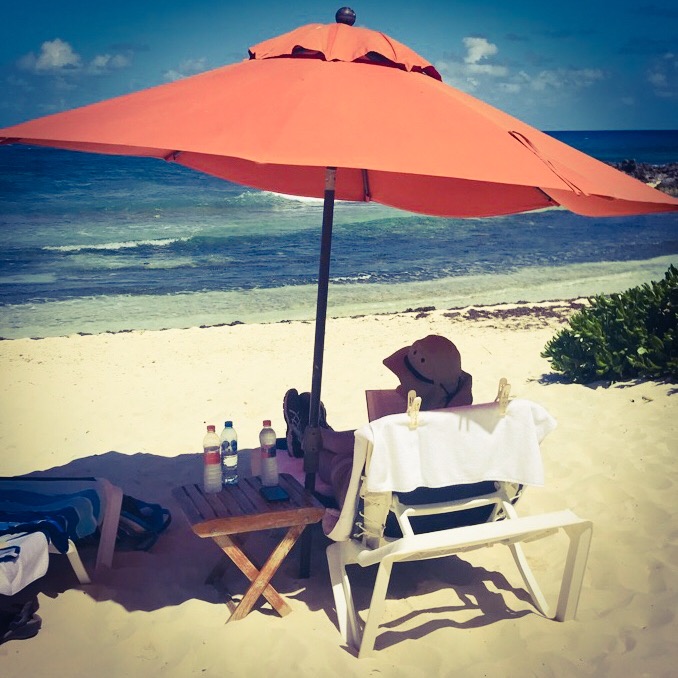Man sitting under a beach umbrella overlooking the ocean