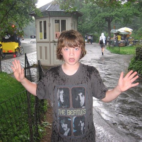 Boy wearing a Beatles tshirt in the rain in Central Park New York City