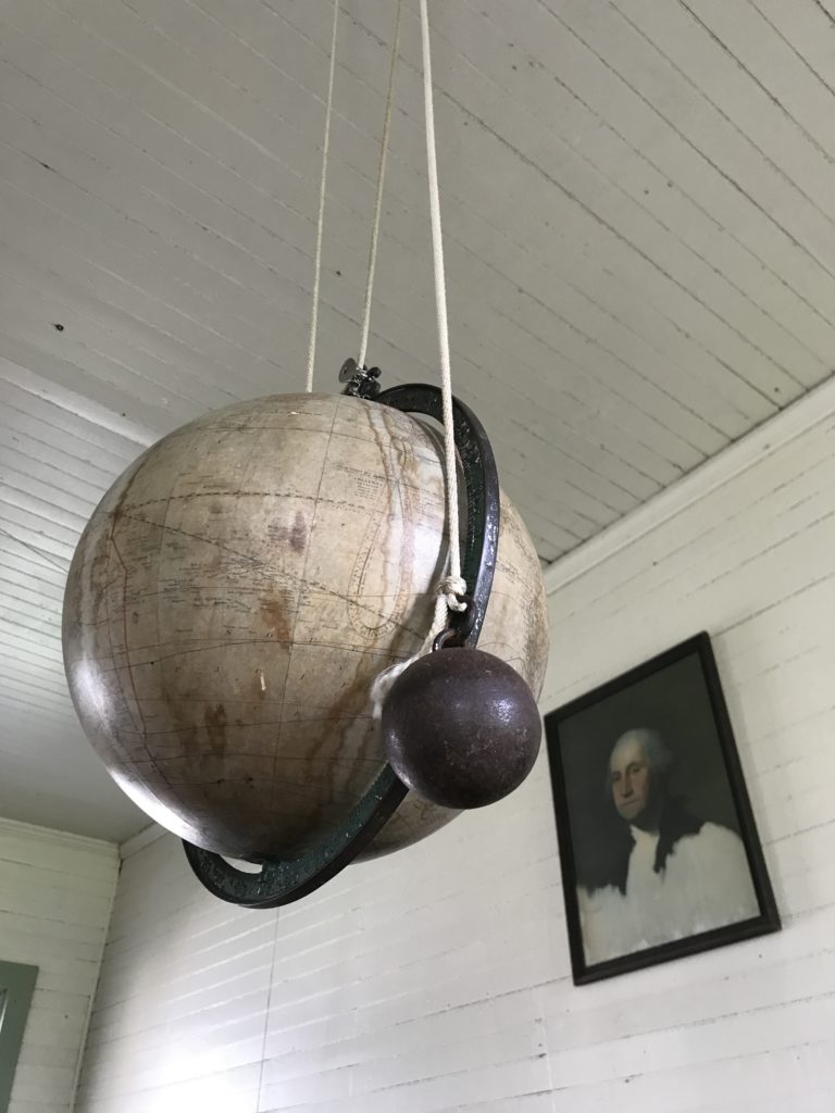 World globe hanging from ceiling with portrait of George Washington hanging on the wall
