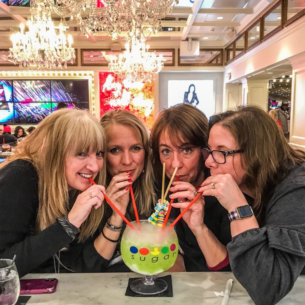 Mall of America happy hour for hockey moms. Four women drinking a fishbowl drink at Sugar Factory.