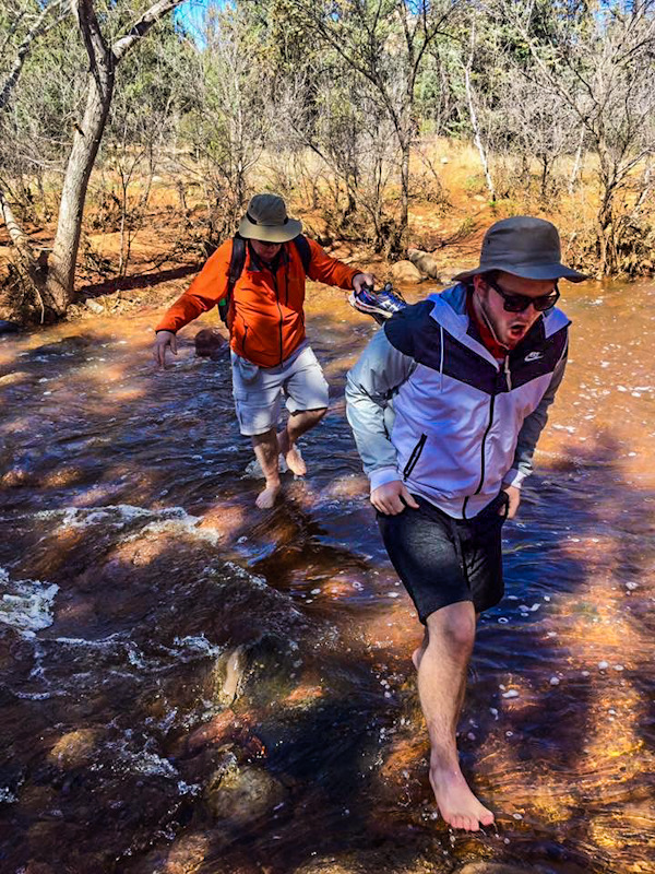 2 men wading through cold water on Devil's Bridge Trail in Sedona, Arizona