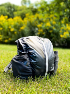 backpack in grass in front of yellow foliage