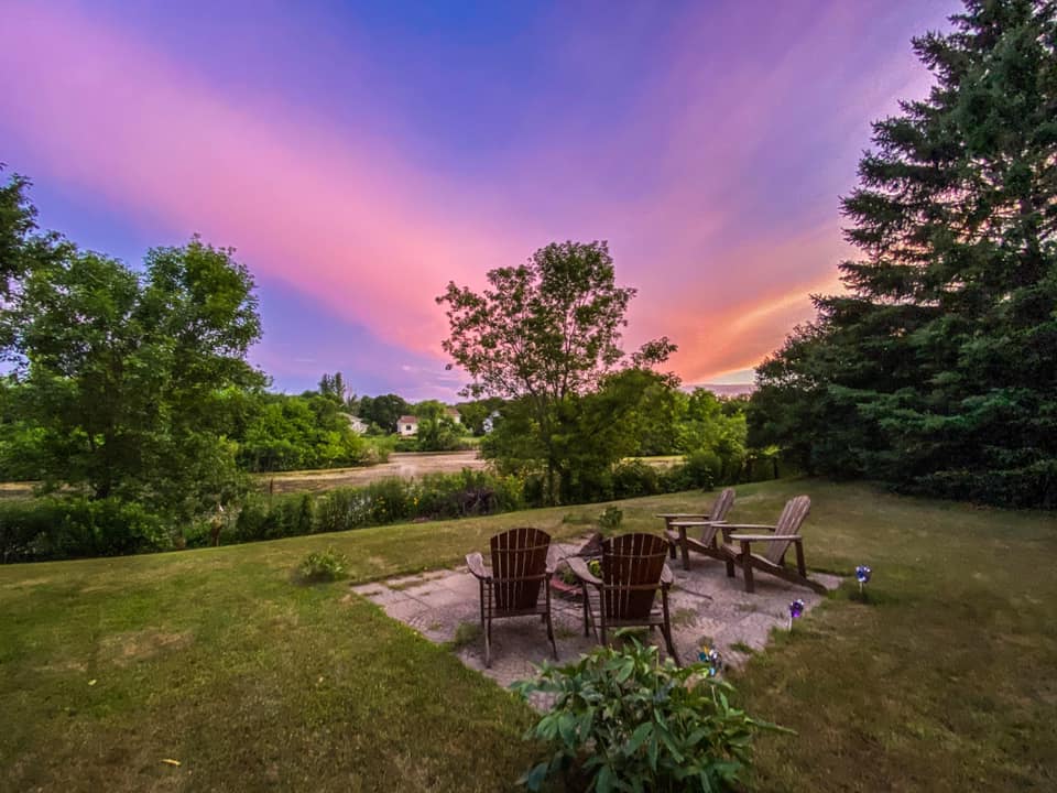 Adirondack chairs in backyard with sunset