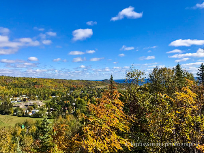Scenic overlook of town and fall foliage and trees with blue sky and a few clouds