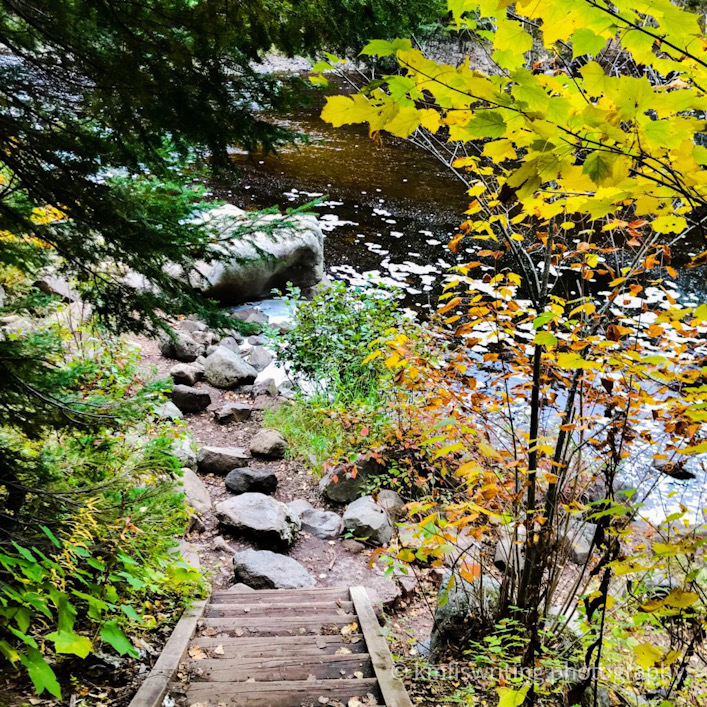 Stairs leading down to a river with trees turning fall colors