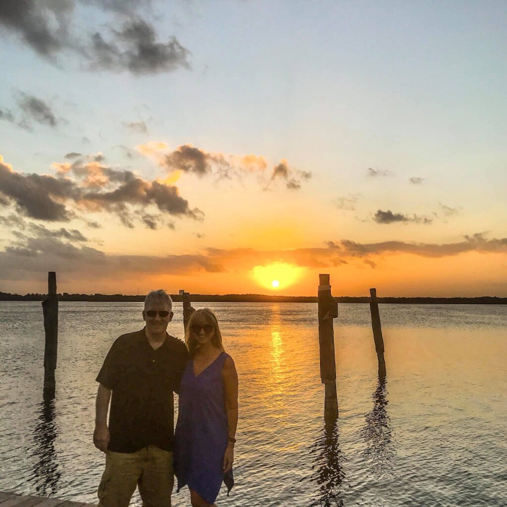 couple standing on dock overlooking lagoon at sunset