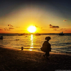 Woman walking on beach at sunset
