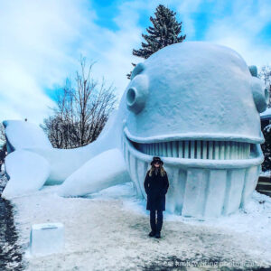Woman standing in front of a giant whale snow sculpture