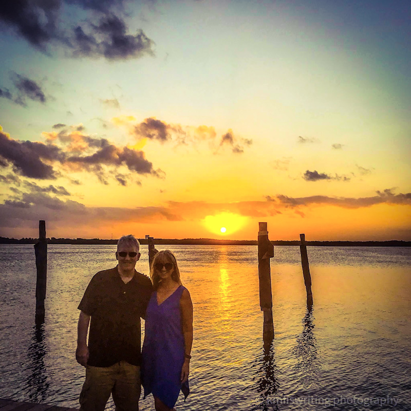 Couple standing on pier at sunset