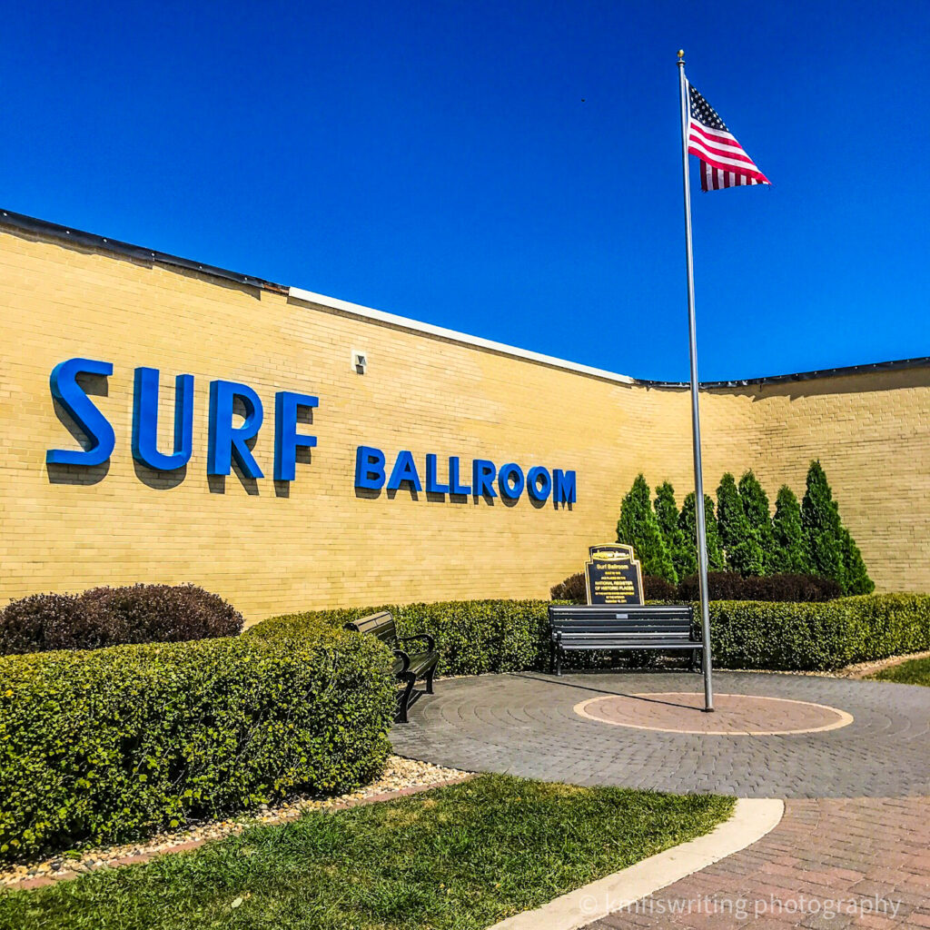 Exterior of Surf Ballroom with flag, park bench and blue sky