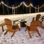 Adirondak chairs in front of a fire pit in snow